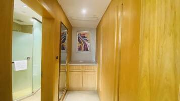 A narrow hallway with wooden paneling and a glass shower enclosure.