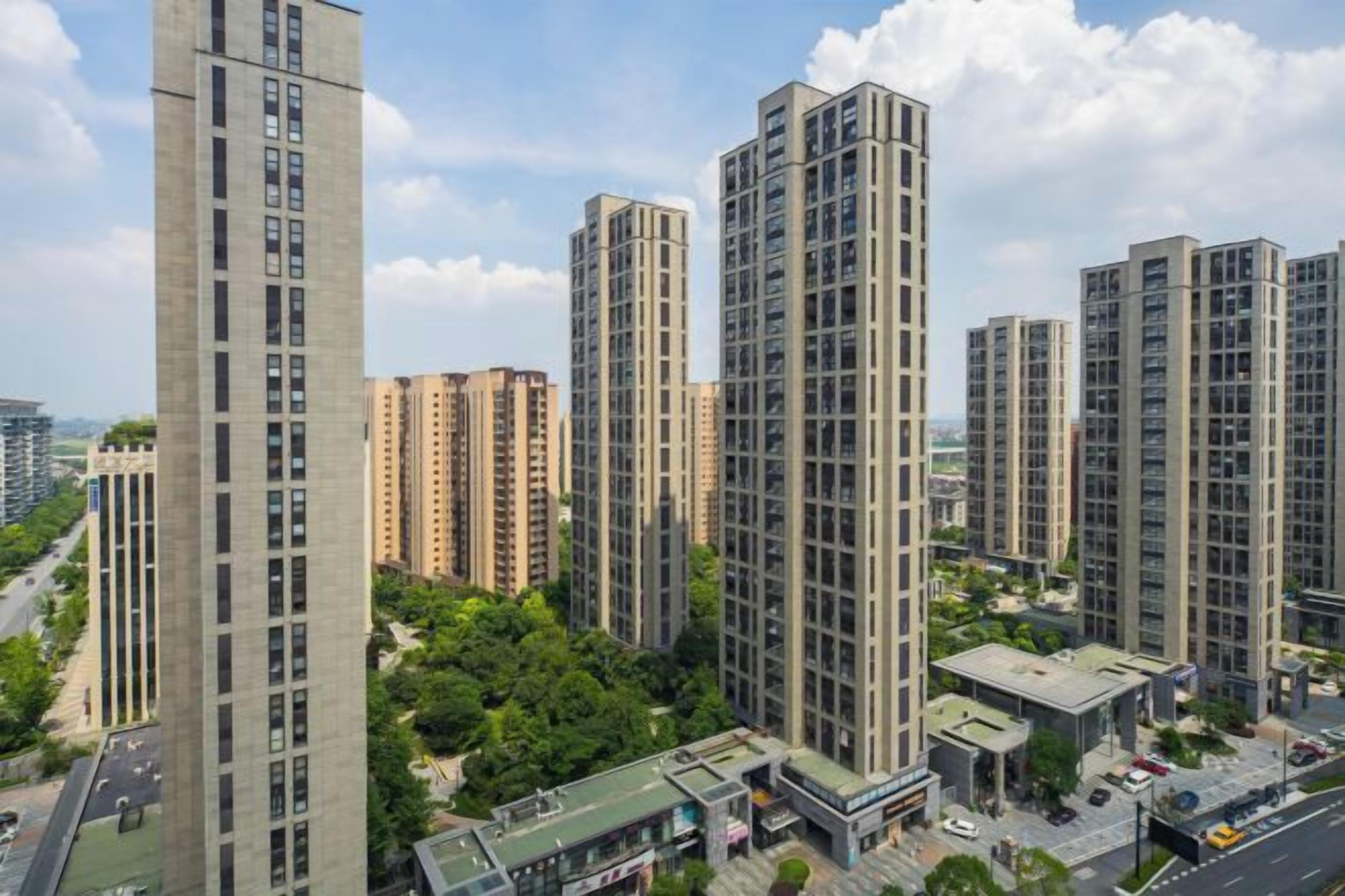 Un complejo residencial de edificios altos, con varios edificios de apartamentos, un patio central y una calle en primer plano.