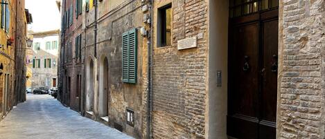 Una calle estrecha con edificios de piedra, una puerta de madera y un cartel en la pared.