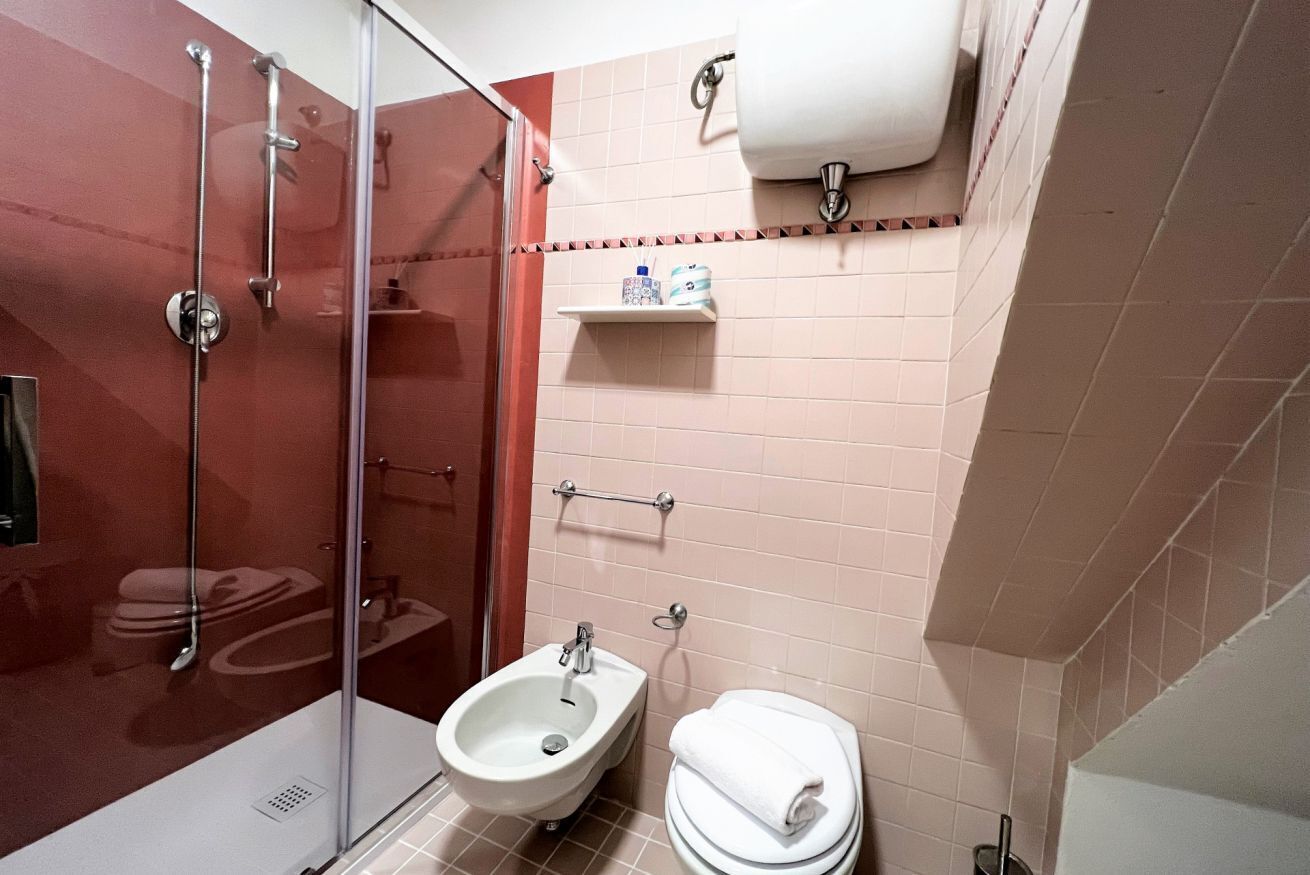 Un baño con ducha envuelta en vidrio, un bidé, un inodoro y un perchero para toallas.
