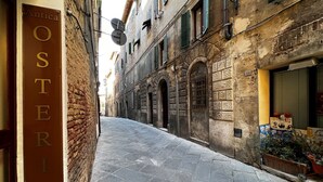 A narrow street with a sign for "OSTERIA DA DIVO" on the left. - The little house on franciosa street (Siena)