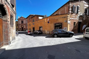 A narrow street with historic buildings, a parked car, and a visible storefront. - Sperandie—within the city walls (Siena)