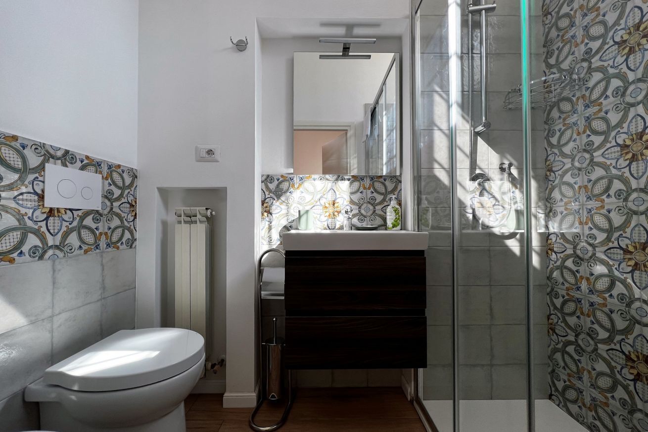 Une salle de bain moderne comprenant des toilettes, un lavabo avec un meuble sombre et un espace douche.