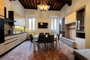 A modern kitchen with a dining table, chairs, and a TV mounted on the wall. - Sperandie—within the city walls (Siena)
