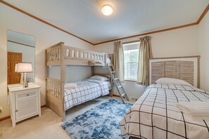 Een slaapkamer met stapelbedden, een bureau, een spiegel en een raam met gordijnen.