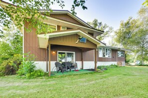 A two-story house with a covered patio, a dining area with chairs, and a small garden. - Riverfront Sault Ste Marie Home w/ Dock! (Sault Ste. Marie)