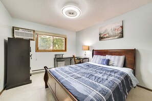A bedroom with a bed, a desk, a chair, a lamp, and a painting on the wall. - Riverfront Sault Ste Marie Home w/ Dock! (Sault Ste. Marie)