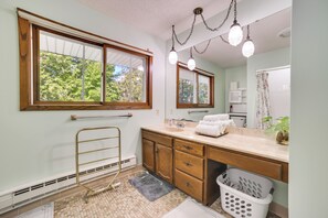 A bathroom with a wooden vanity, a large window, and a mirror. - Riverfront Sault Ste Marie Home w/ Dock! (Sault Ste. Marie)
