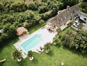 Vue aérienne d’une propriété résidentielle dotée d’une piscine, de meubles de patio et d’un espace extérieur couvert.