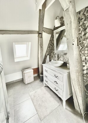 A bathroom with a white vanity, a mirror, and a patterned wall.
