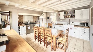 Een ruime keuken met houten stoelen, een eettafel en witte kastjes.