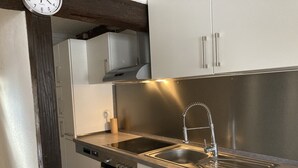 A modern kitchen with stainless steel appliances, a double sink, and wooden cabinets. - Family-friendly apartment in an old farmhouse (Steißlingen)
