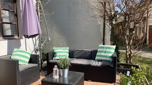 An outdoor patio area with wicker furniture, a table, and a potted plant. - Family-friendly apartment in an old farmhouse (Steißlingen)