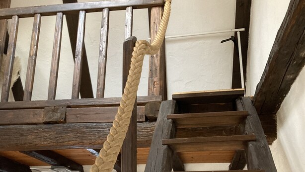 A wooden staircase with a rope handrail, a couch, and a white wall. - Family-friendly apartment in an old farmhouse (Steißlingen)