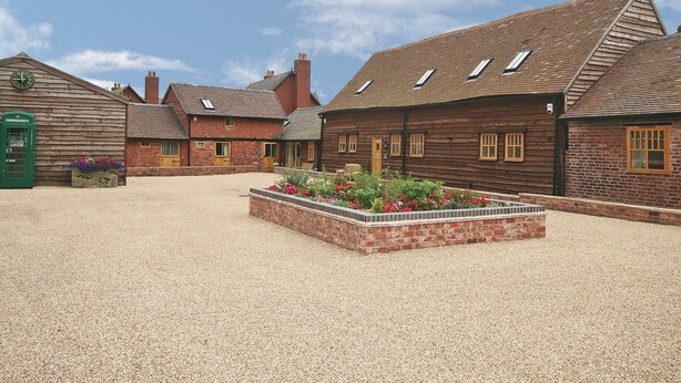 A traditional wooden building with a gravel courtyard and flower beds.