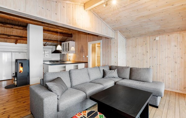 A modern interior with a grey sectional sofa, a black coffee table, and a wood-paneled ceiling. - 4 bedroom cozy home in Meisingset (Meisingset)