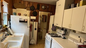 A kitchen with white appliances, wooden walls, and a wooden floor. - Cabin with private lake access on Cedar Cliff Lake (Tuckasegee)