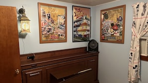 A room with a wooden dresser, a lamp, and three framed posters on the wall. - Cabin with private lake access on Cedar Cliff Lake (Tuckasegee)