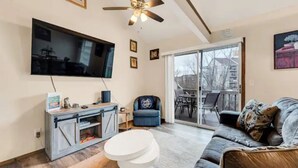 Un salon équipé d’un téléviseur à écran plat, d’un ventilateur de plafond, d’un canapé, d’une table basse et d’une porte-fenêtre coulissante donnant sur un balcon.