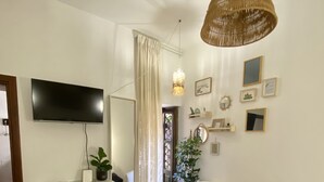 Ett modernt sovrum med en säng, en tv, en byrå, en stol och en hängande lampa.