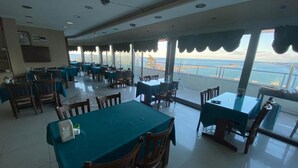 A restaurant with tables and chairs, large windows with ocean views, and a tiled floor. - Ganita Life Hotel (Trabzon)