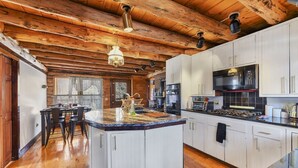 A spacious kitchen with wooden beams, a large island, and modern appliances. - Berkshire Mountain Top Chalet (North Adams)