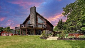 A log cabin with a stone chimney, a balcony, and a covered patio. - Berkshire Mountain Top Chalet (North Adams)
