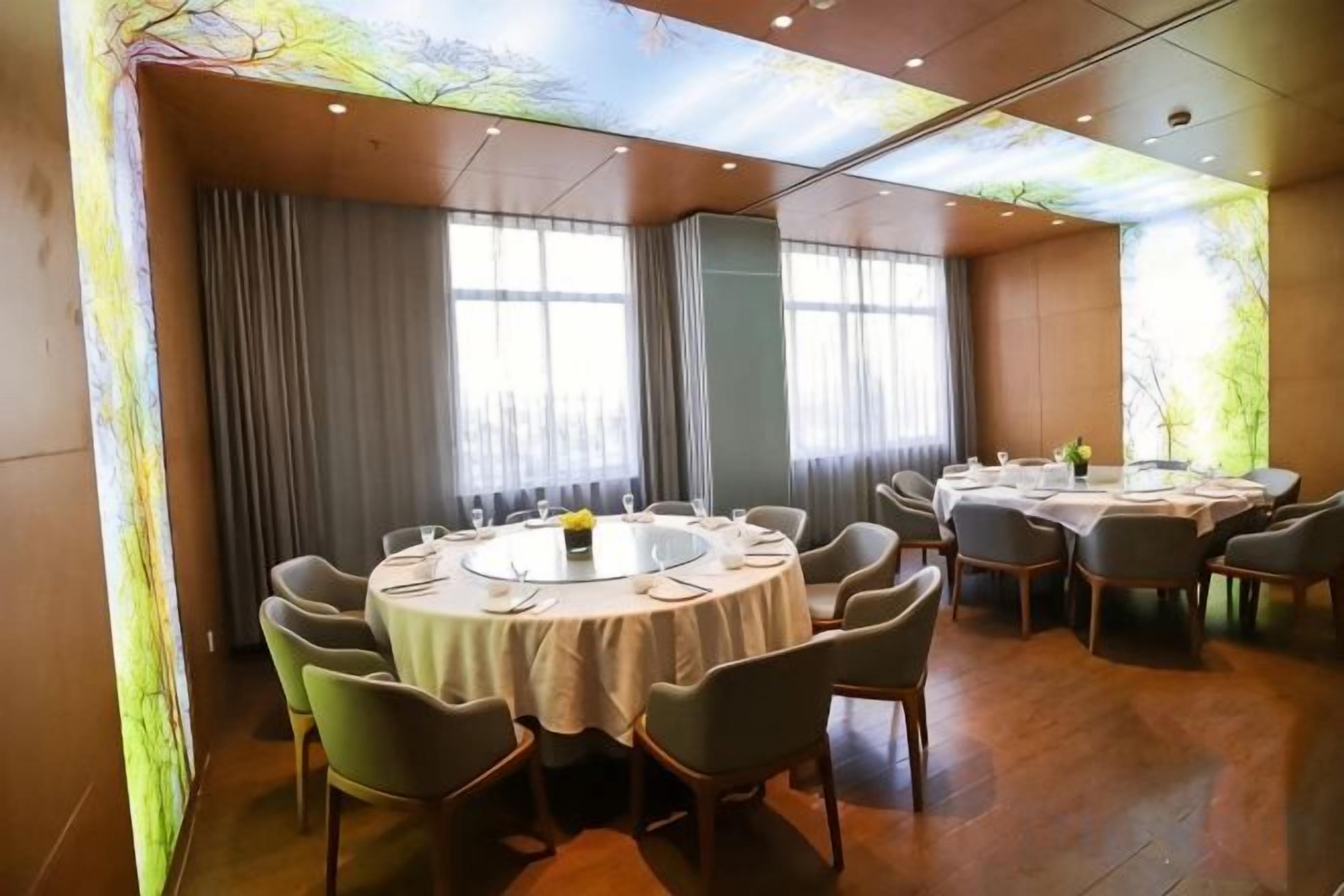 A conference room with round tables, chairs, and a large window with curtains.