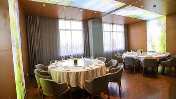 A conference room with round tables, chairs, and a large window with curtains.