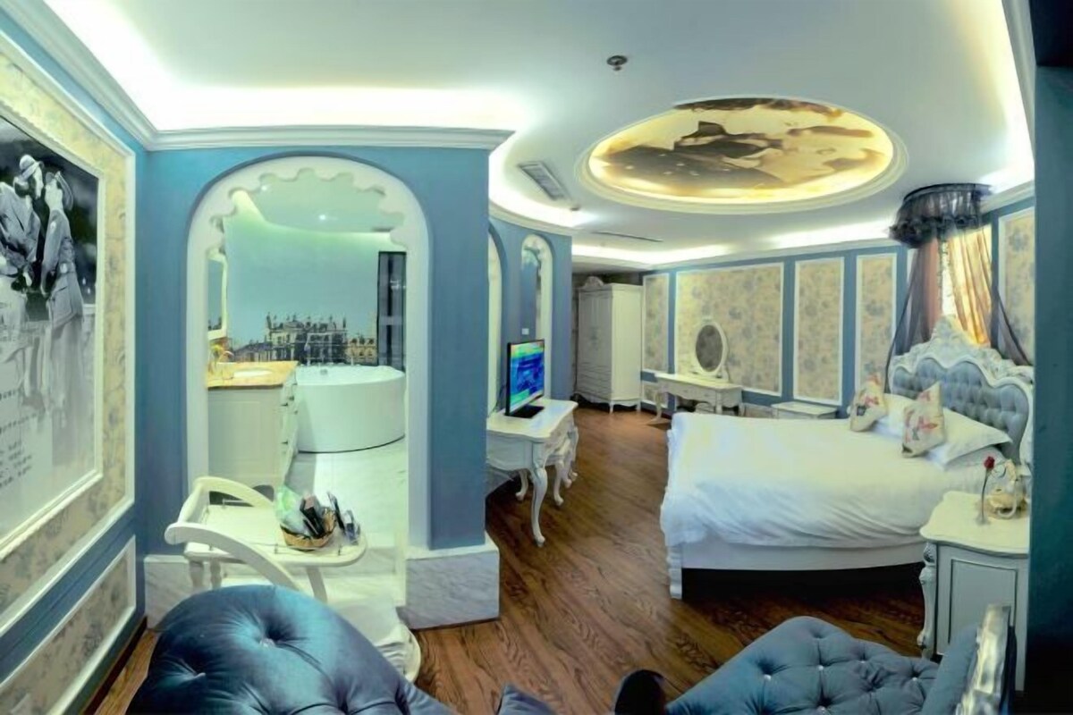Una habitación de hotel con una cama grande, un escritorio con computadora, una silla y un televisor.