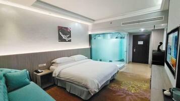 A modern hotel room with a bed, a small bedside table, a chair, and a shower area.