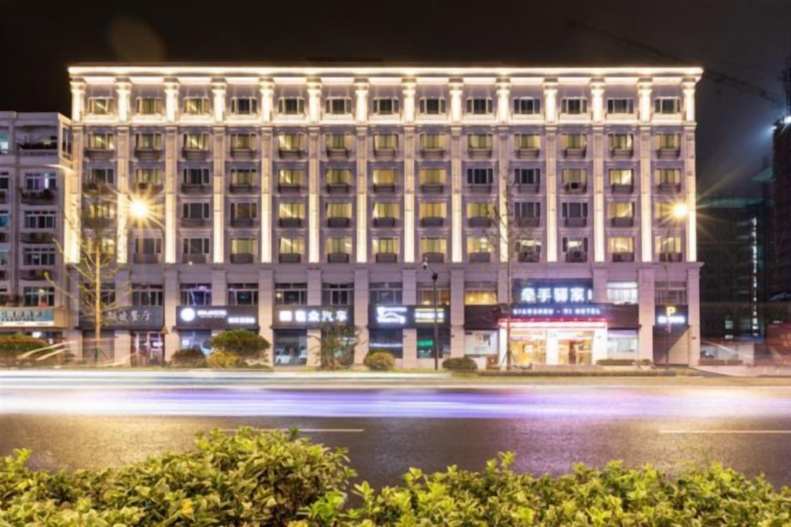 A multi-story hotel with a symmetrical facade, large windows, and illuminated signage.