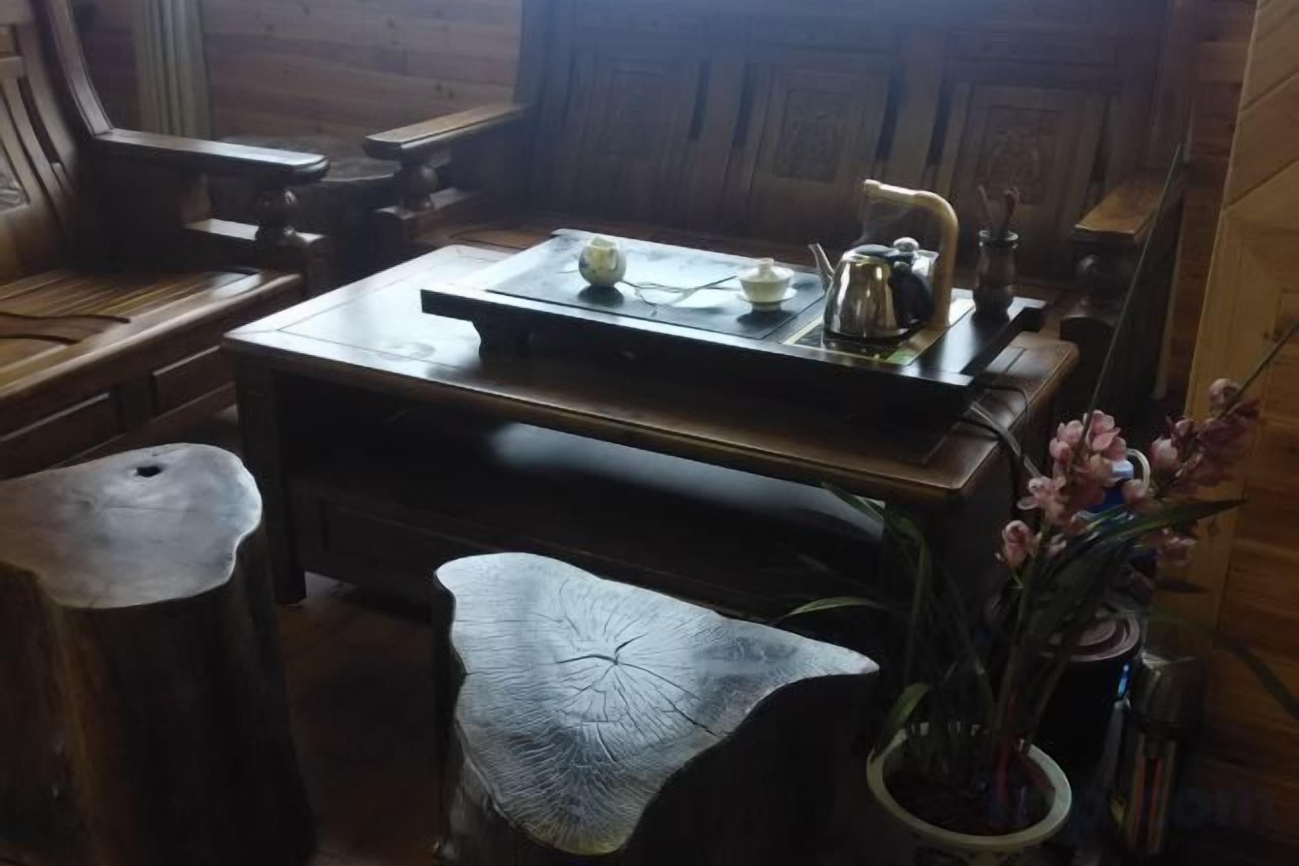A wooden dining table with a teapot and cups, a vase with flowers, and a rustic wooden bench.