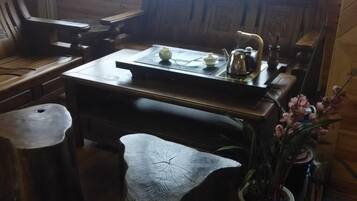 A wooden dining table with a teapot and cups, a vase with flowers, and a rustic wooden bench.