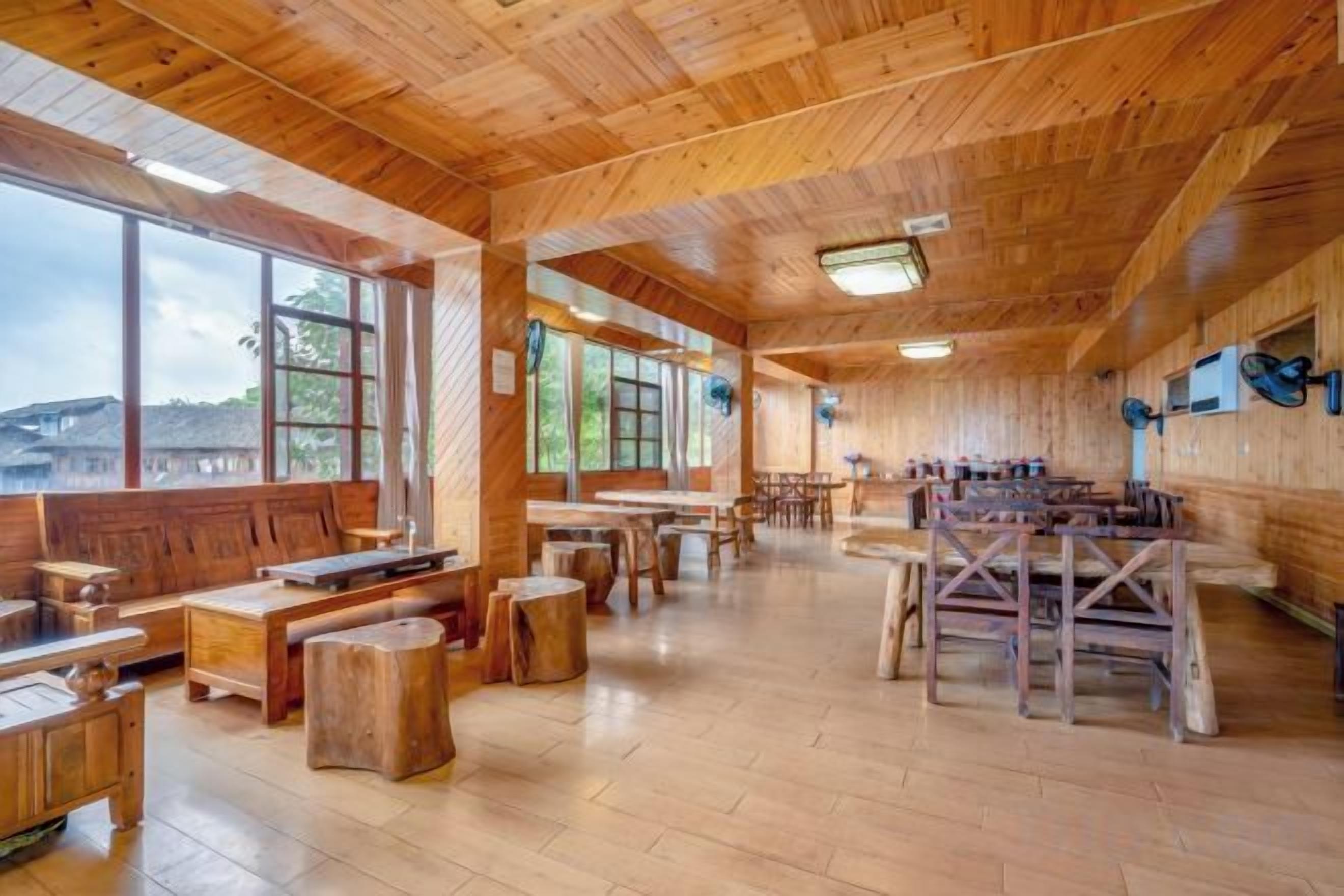 Un interior espacioso de madera con ventanas amplias, muebles de madera y vistas al exterior.