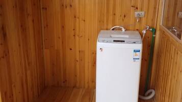A small, white, compact washer and dryer unit in a wooden room with a wooden floor.