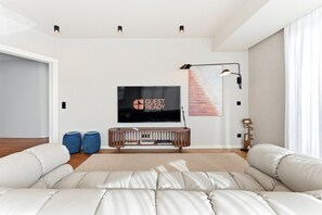 A modern living room with a large flat-screen TV, a wooden console table, and a beige sofa.