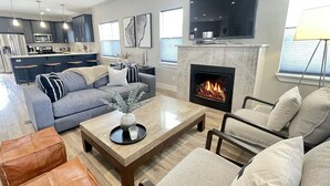 A modern living room with a fireplace, a sofa, a coffee table, and a television. - Pristine Home Near Sun Valley (Hailey)