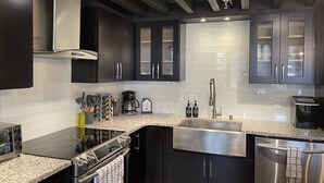 A modern kitchen with dark cabinets, stainless steel appliances, and a granite countertop. - Golf Getaway with Golf Cart on Grand Lake in Shangri-La (Afton)