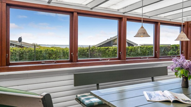 A room with large windows, a bench, a table, and a hanging lamp. - 2 bedroom awesome home in Faaborg (Faaborg)