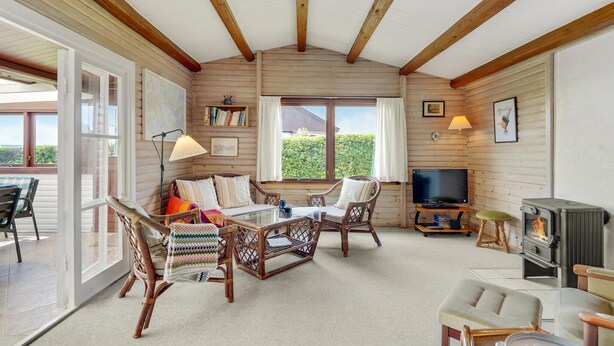 A cozy room with a wooden ceiling, a large window, a television, and a fireplace.