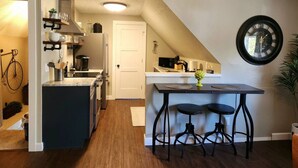 Una cocina compacta con una isla central, un comedor con taburetes y un reloj en la pared.