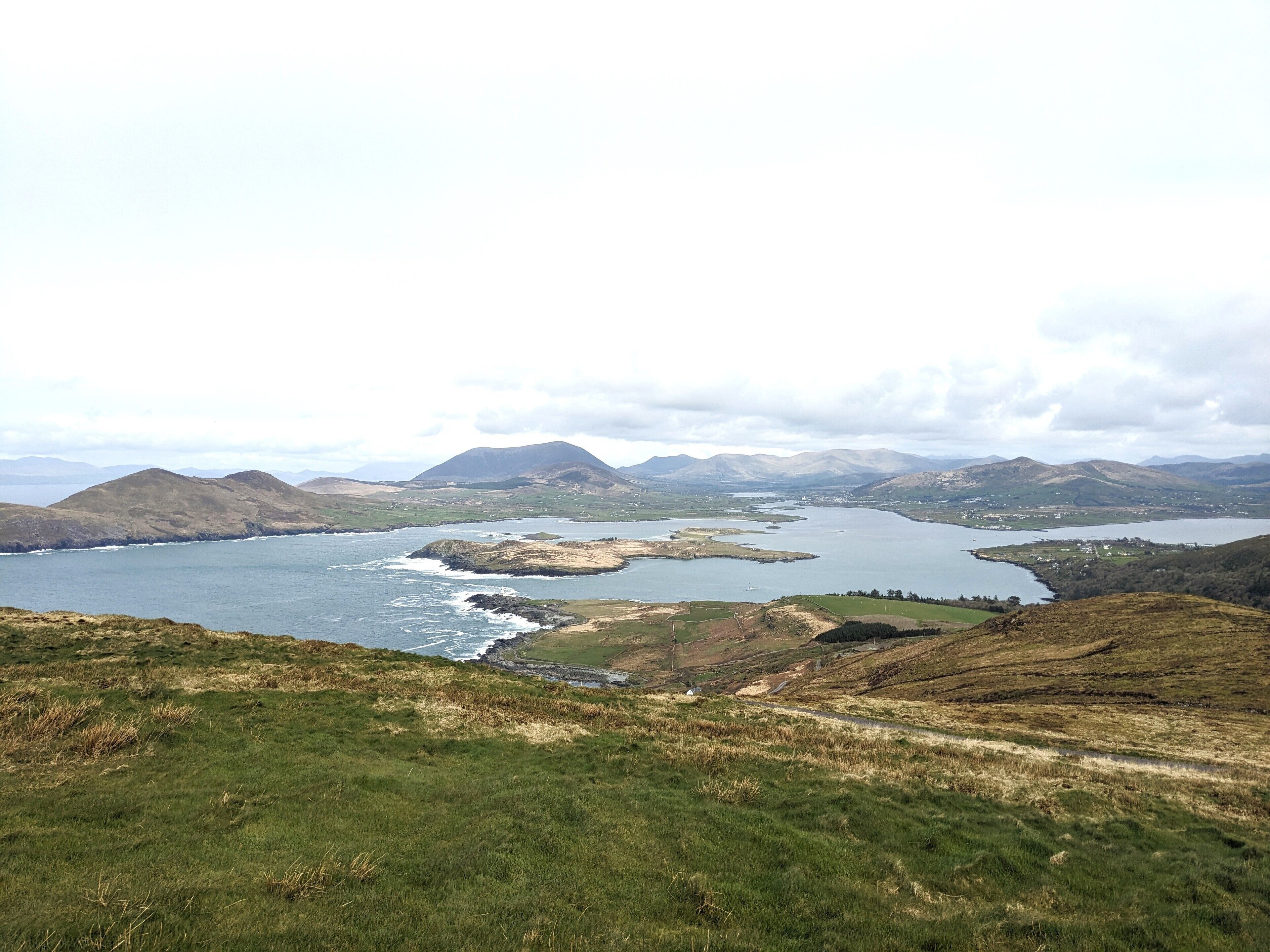 A coastal landscape with a large body of water, hills, and a clear sky.