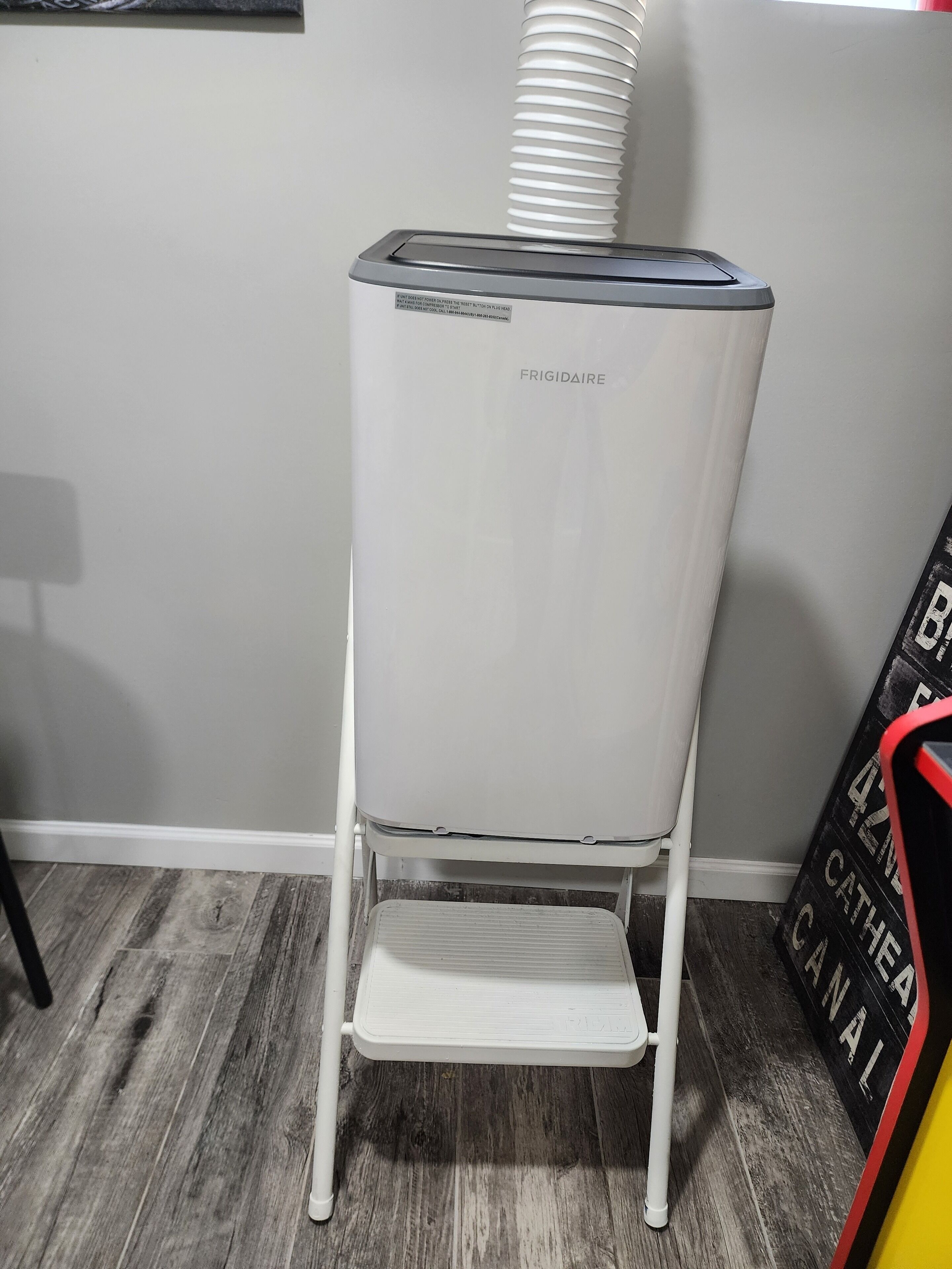A white refrigerator with a step stool in front of it.