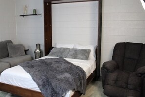 Cozy retreat with a four-poster bed, armchair, and decorative shelf.
