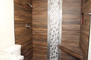 Enjoy a refreshing shower in this bathroom featuring a walk-in shower with a decorative tile accent wall.