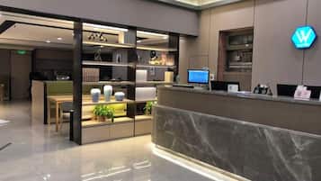 A hotel reception area with a marble counter, a reception desk, and a display of decorative items.