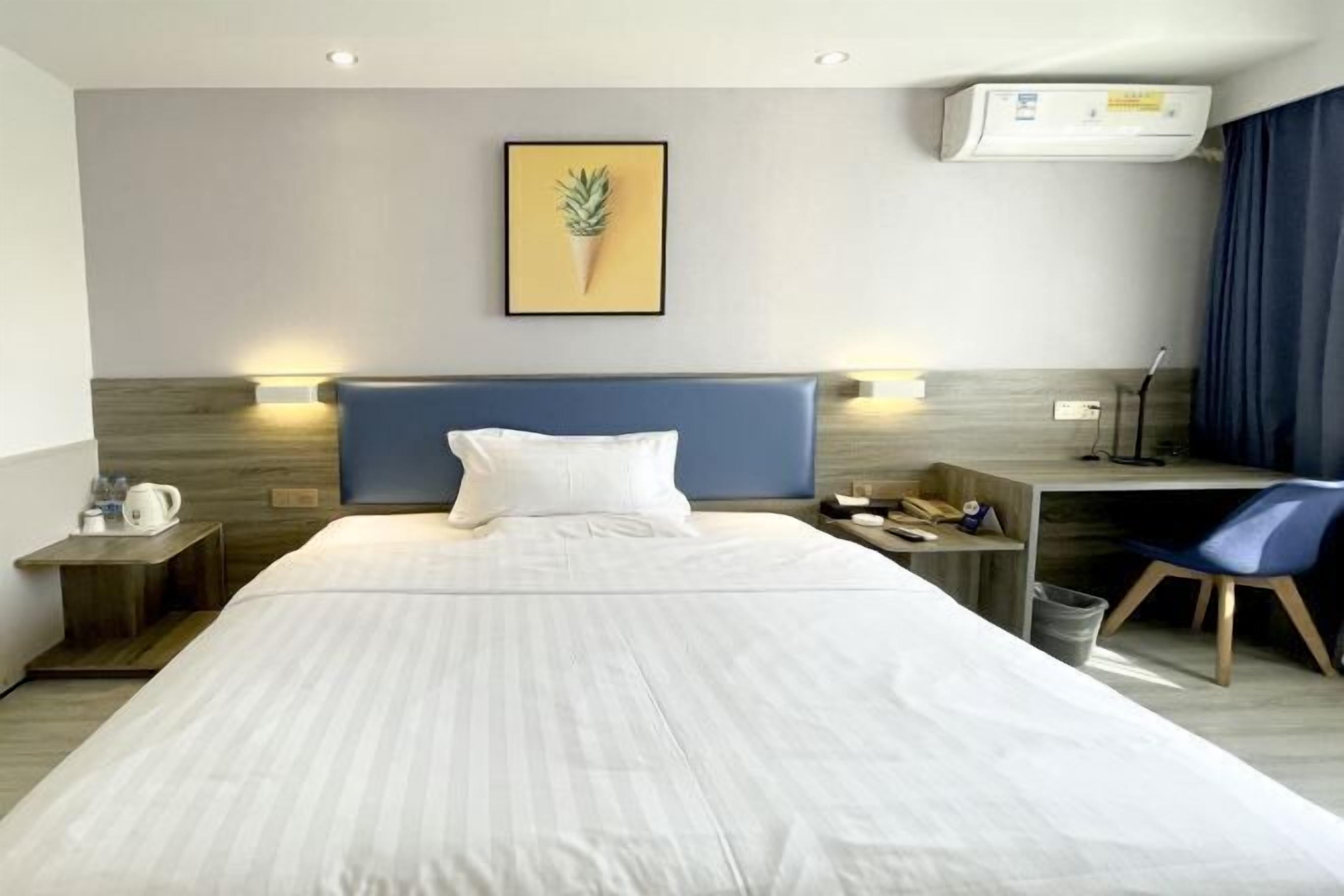 Ein Hotelzimmer mit einem großen Bett, einem Schreibtisch, einem Sessel, einer Kaffeemaschine und einem Bild an der Wand.
