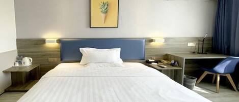Habitación de hotel con una cama grande, un escritorio, una silla, una cafetera y un cuadro en la pared.