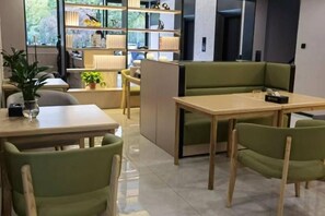 Un interior moderno con una zona de comedor que presenta sillas tapizadas en verde y una mesa de madera.